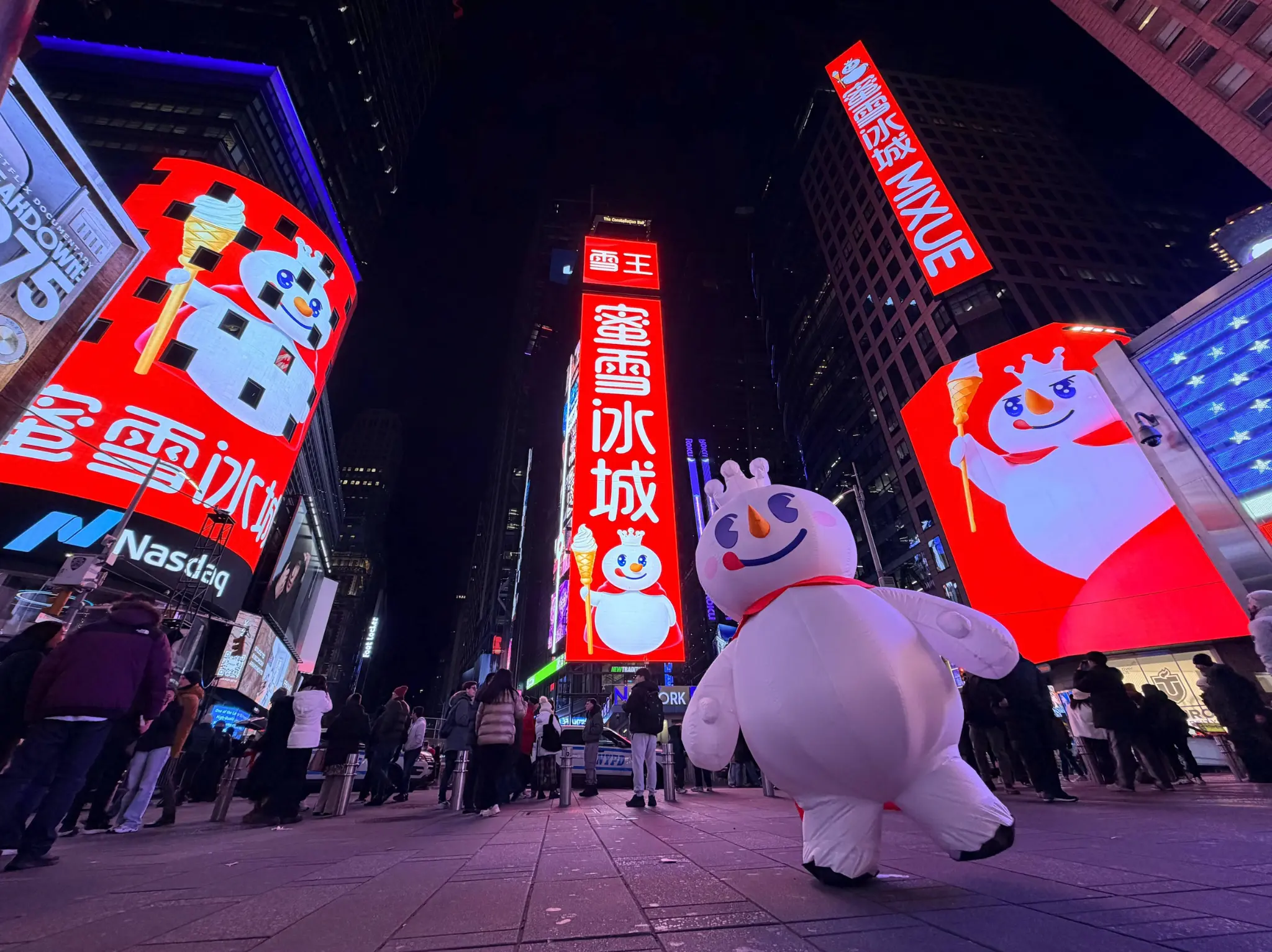 MIXUE brand billboard displayed in Times Square New York at night, showing the iconic snowman mascot and brand logo